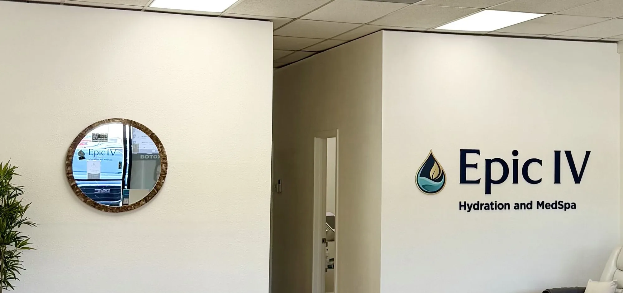 Round mirror and the hallway to the private treatment rooms at Epic IV, with the Epic IV wordmark on the wall