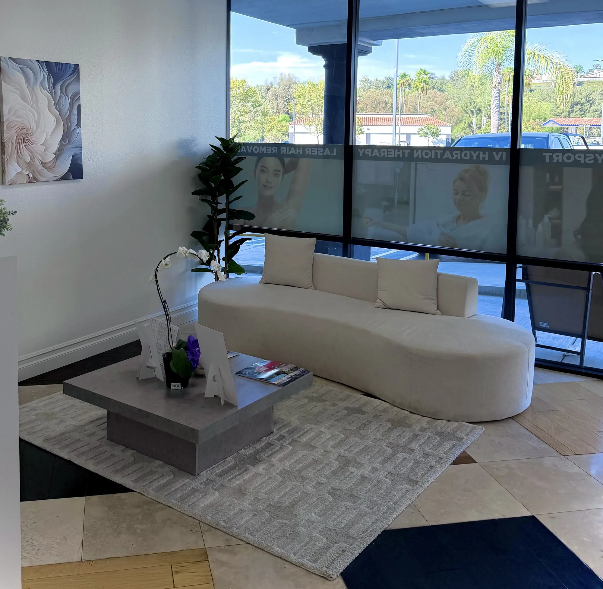 Waiting lounge with a curved cream sofa, an orchid and windows onto palm trees at Epic IV
